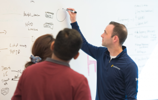 three employees working on a white board