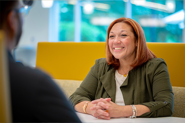 CC-4 Synchrony woman employee sitting at table smiling with another employee