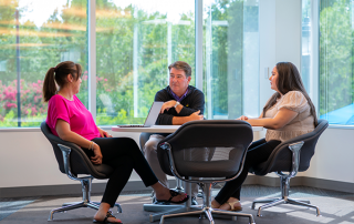 CS-2 three employees sitting at a table conversating