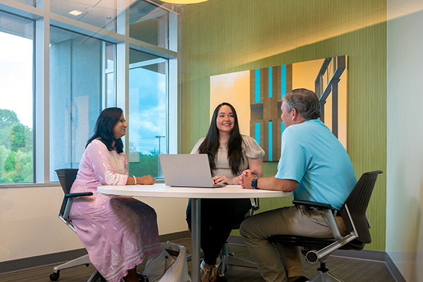 two women and man sitting at table working together