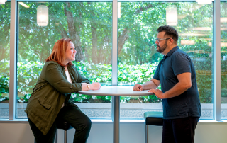 man and woman sitting at table talking to each other